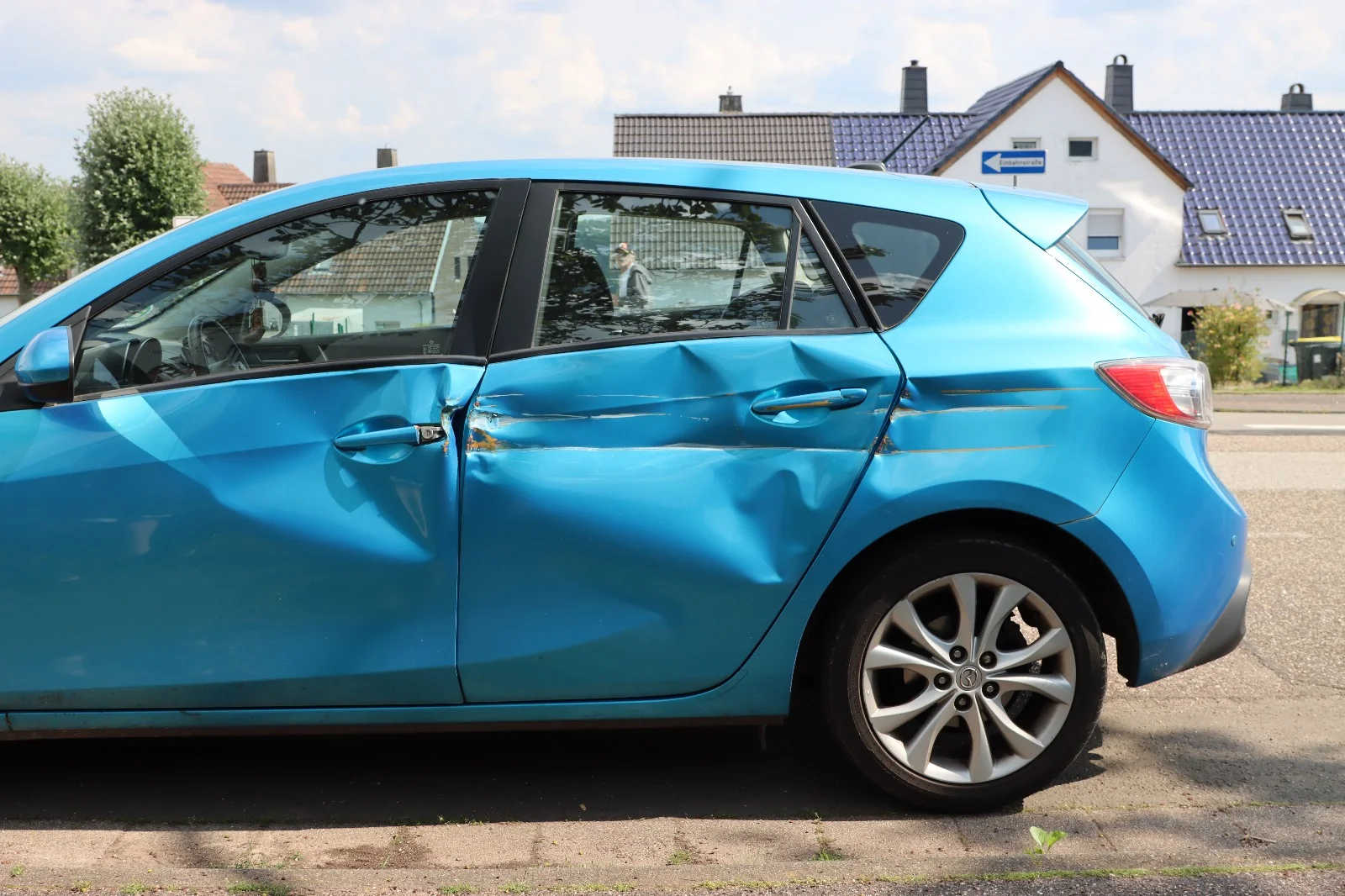 Bild einer beschädigten Seite eines blauen Autos